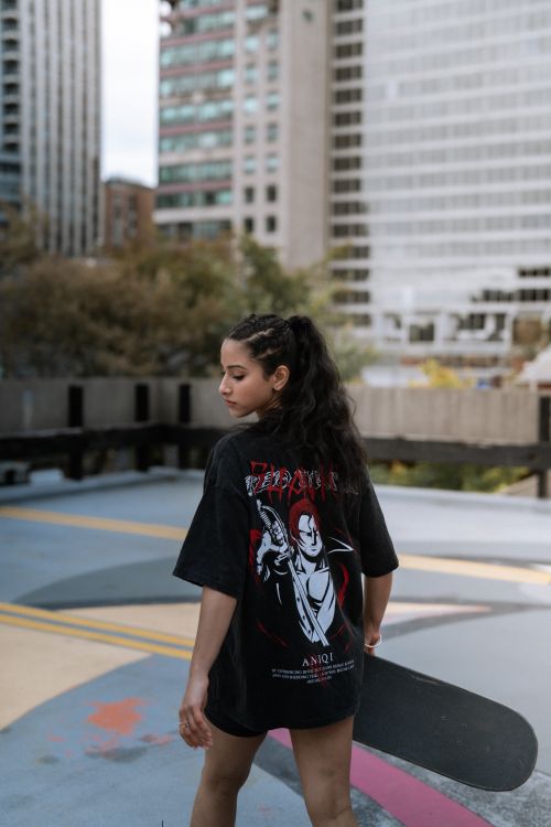 Free A young woman holding a skateboard stands on an urban rooftop with city buildings in the background. Stock Photo