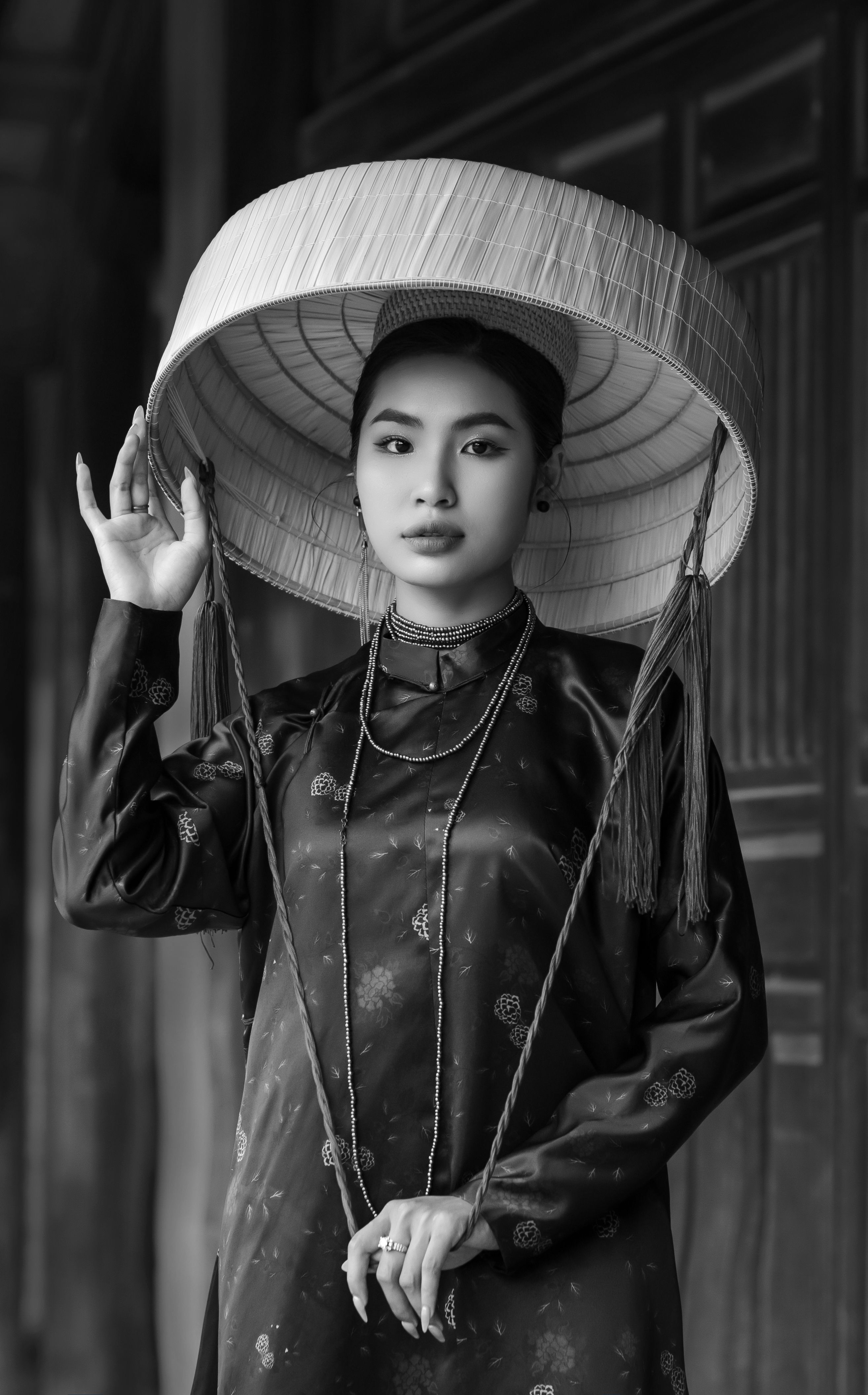 Black and white portrait of a woman in traditional dress and ornate hat.