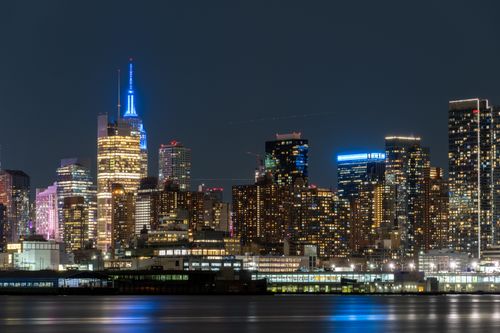 Free Stunning night view of New York City's skyline reflecting on the water, showcasing vibrant urban architecture. Stock Photo