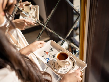 Stylish coffee cup on an illustrated tray, reflecting in the mirror, captured indoors during daylight.