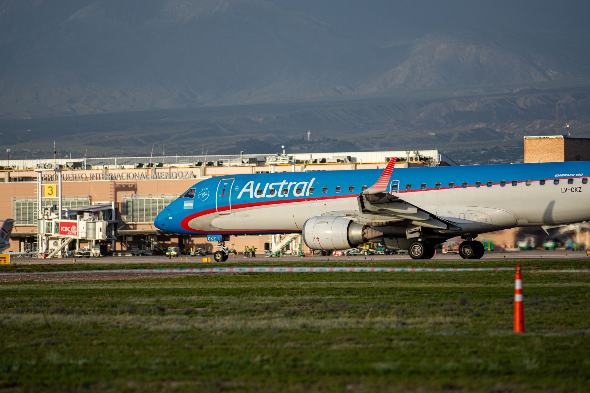 Austral Airlines Embraer aircraft on runway at Mendoza Airport with Andes backdrop.