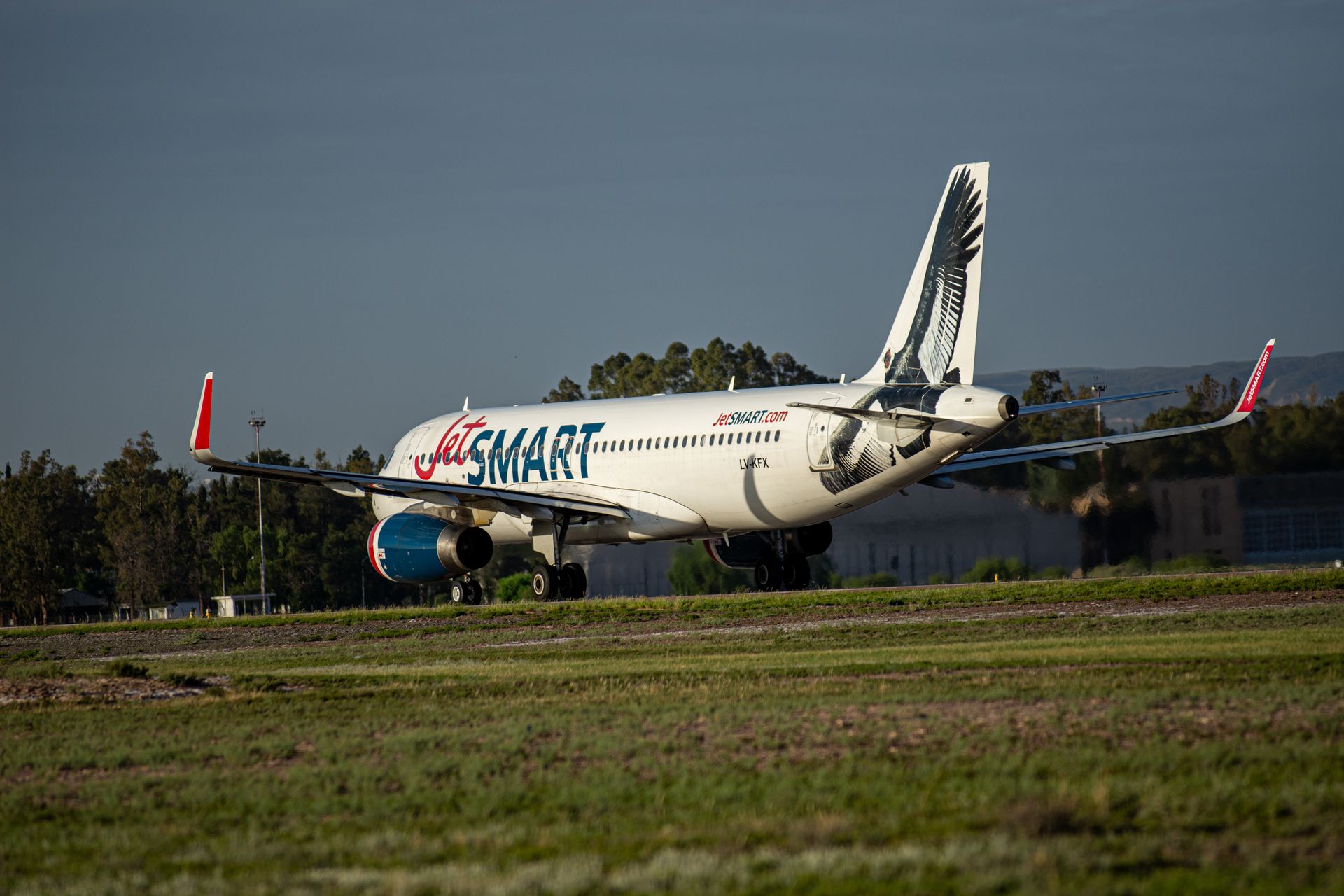 JetSMART aircraft taxiing on runway with distinctive tail design. Clear sky and day setting.