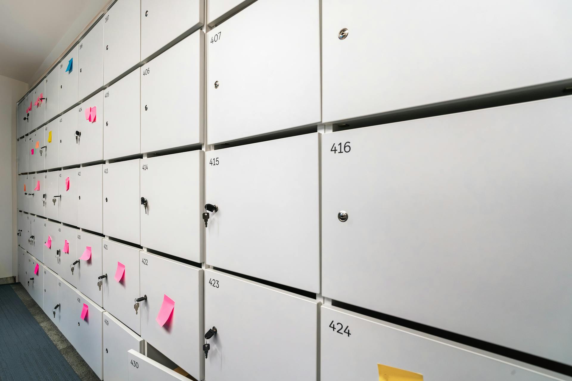 Row of white lockers with colorful sticky notes and numbers, ideal for office organizing theme.