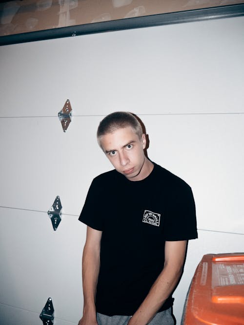 Standing Man Wearing Black Crew-neck T-shirt Leaning on Wall