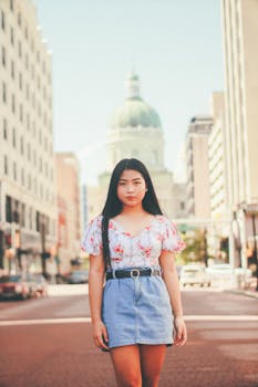 一名穿着休闲夏装的亚洲女子在城市街道上，以标志性建筑为背景摆姿势