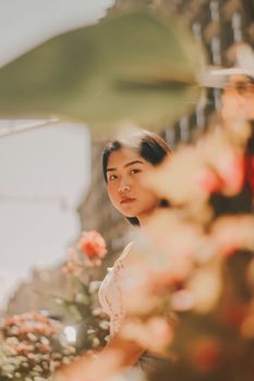 一位亚洲妇女的肖像，以浅景深拍摄，背景是户外鲜艳的花朵