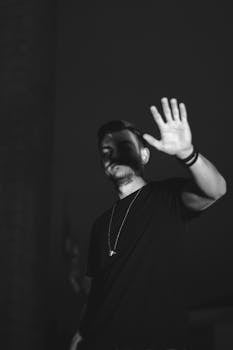 一张男子举手的黑白肖像，营造出神秘而艺术的效果