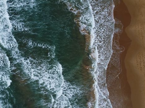 A stunning aerial photo capturing waves crashing onto a pristine sandy beach with vibrant colors.