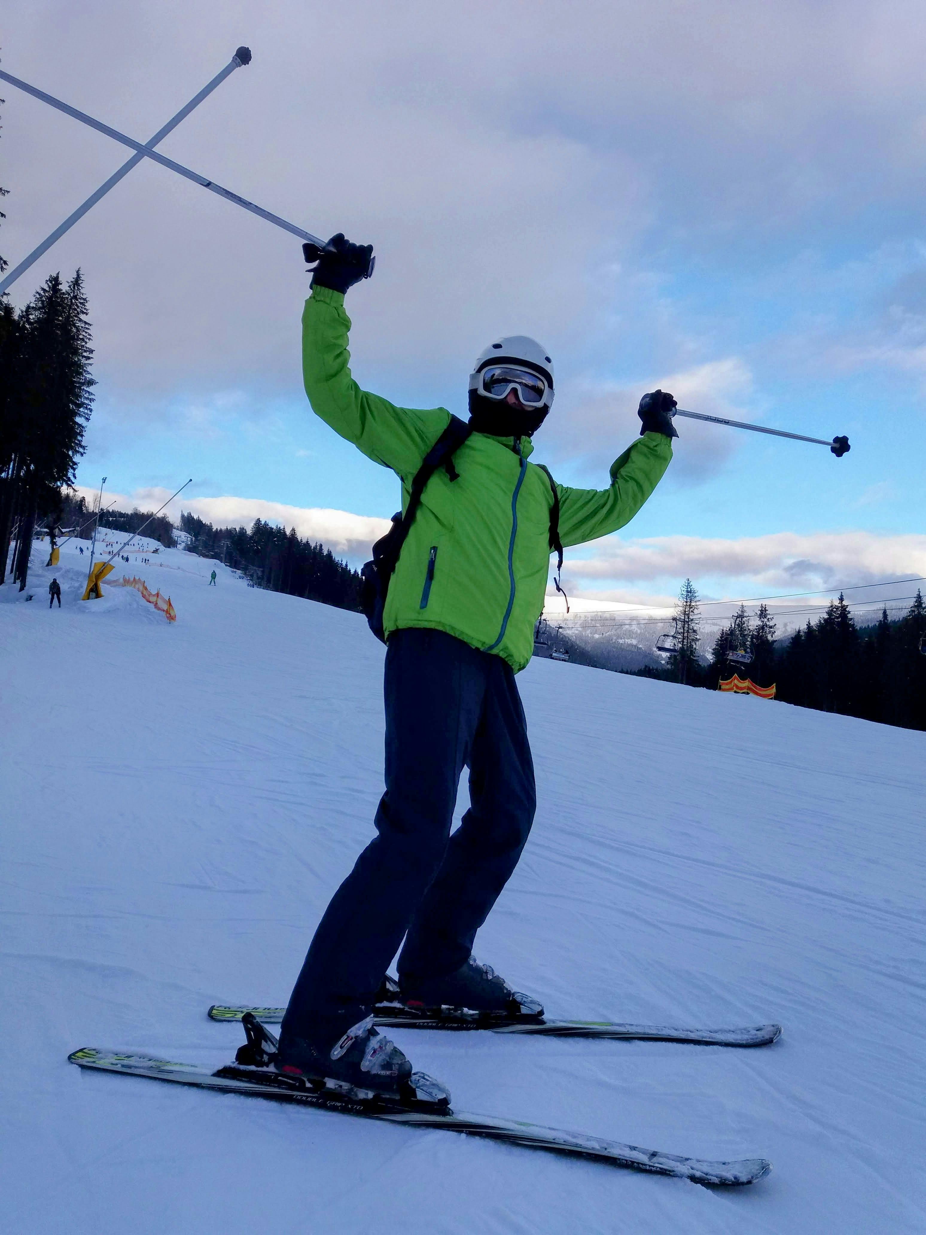 Prescription Goggle Inserts - A skier celebrating on a snowy slope under a bright winter sky, showcasing joy and winter sport fun.