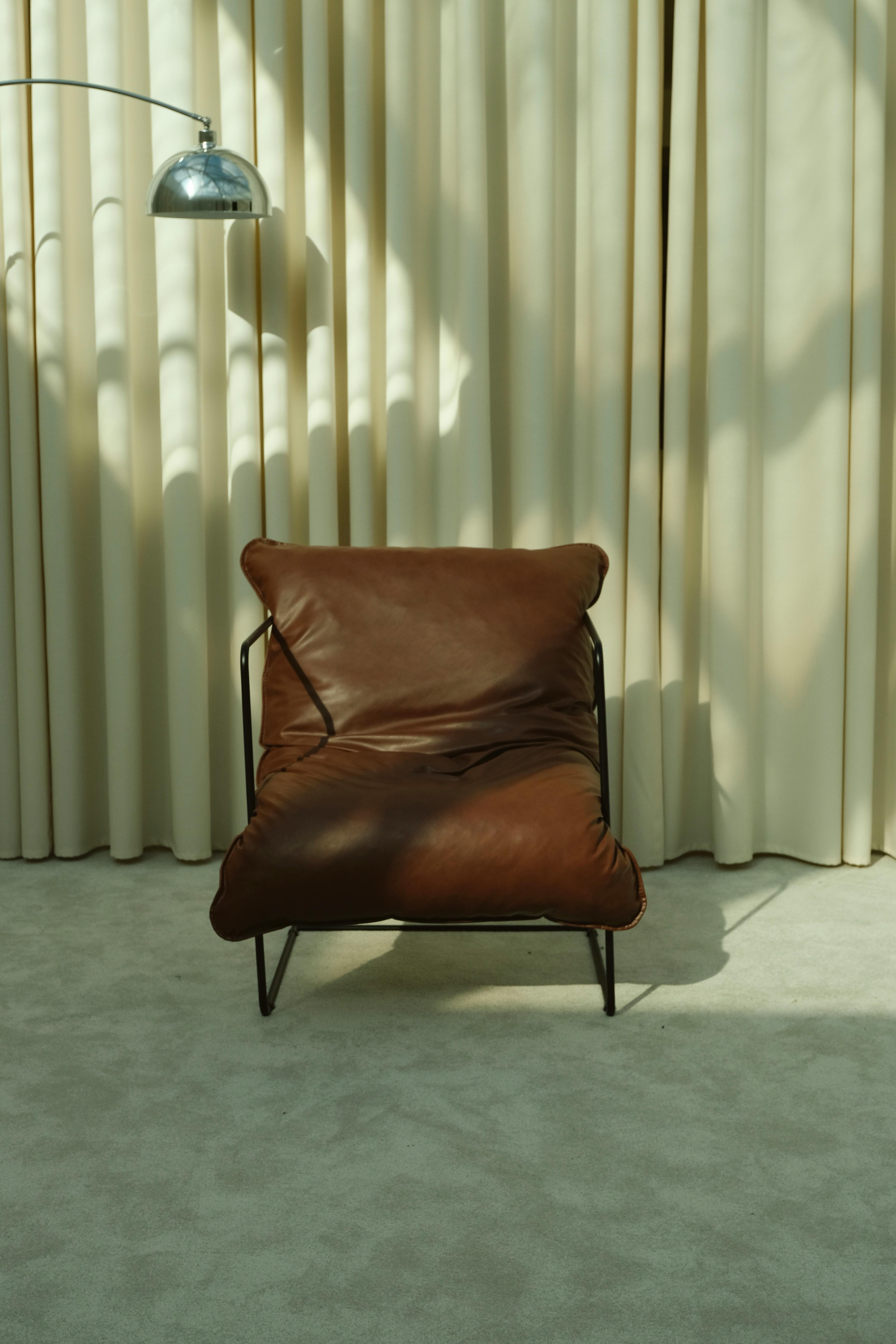Stylish brown leather chair with a retro arc lamp in elegant interior setting.