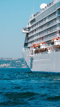 Large cruise ship sailing on the Bosporus Strait in Istanbul under a clear blue sky.