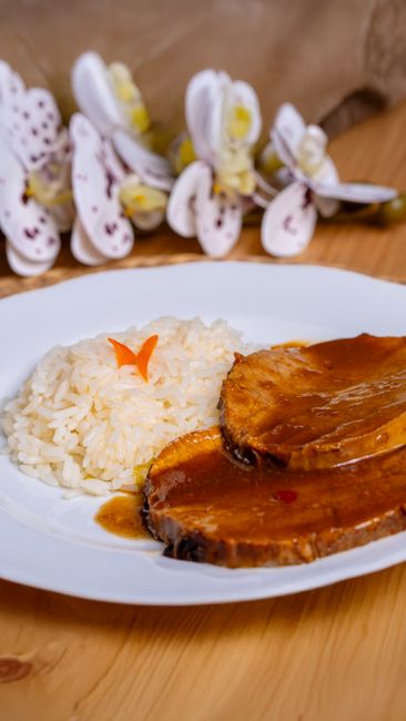 Savory roasted meat with rice garnished with a sauce on a dinner plate. — Porco preto, a Portuguese dish.