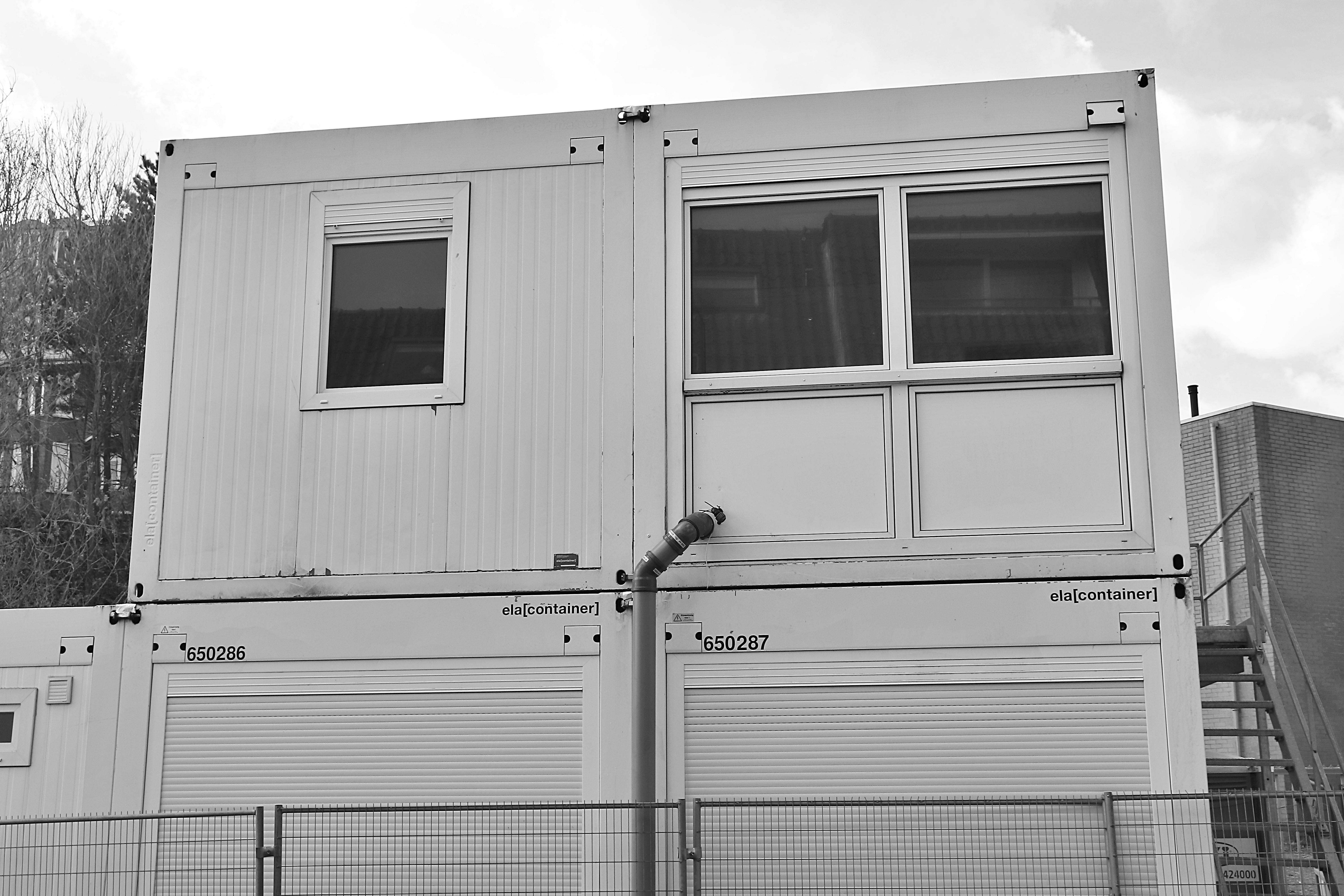 Monochrome image of a stacked container building at a construction site.