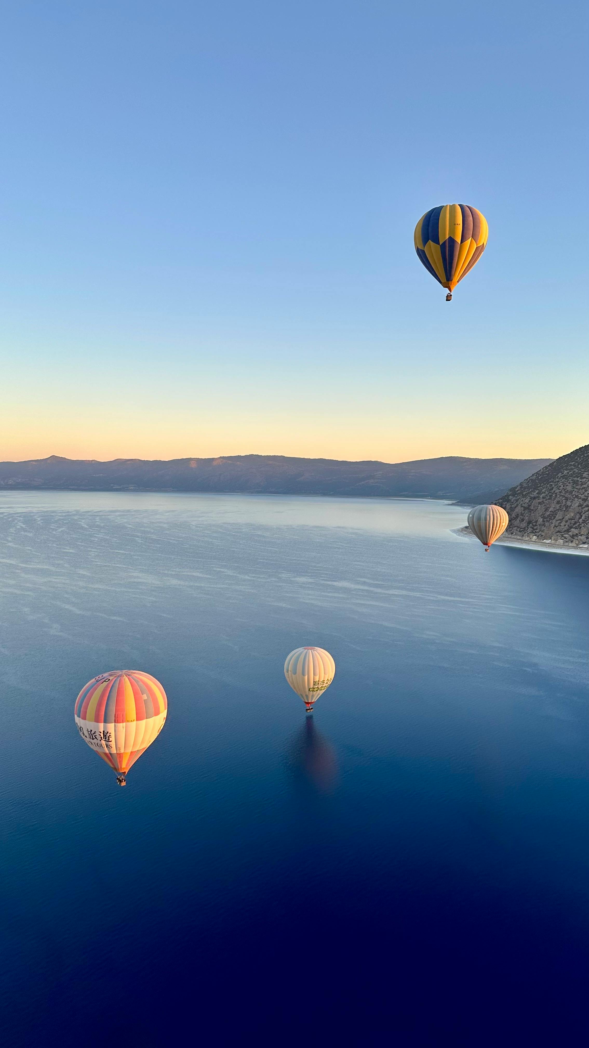 Peaceful hot air balloons rise over the stunning Lake Salda in Burdur, Türkiye during sunrise.