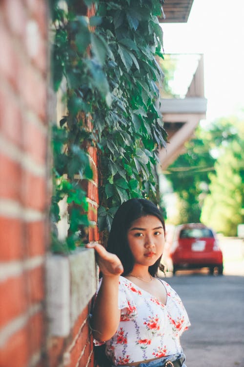 Woman Wearing White and Red Shirt Leaning on Brick Walls