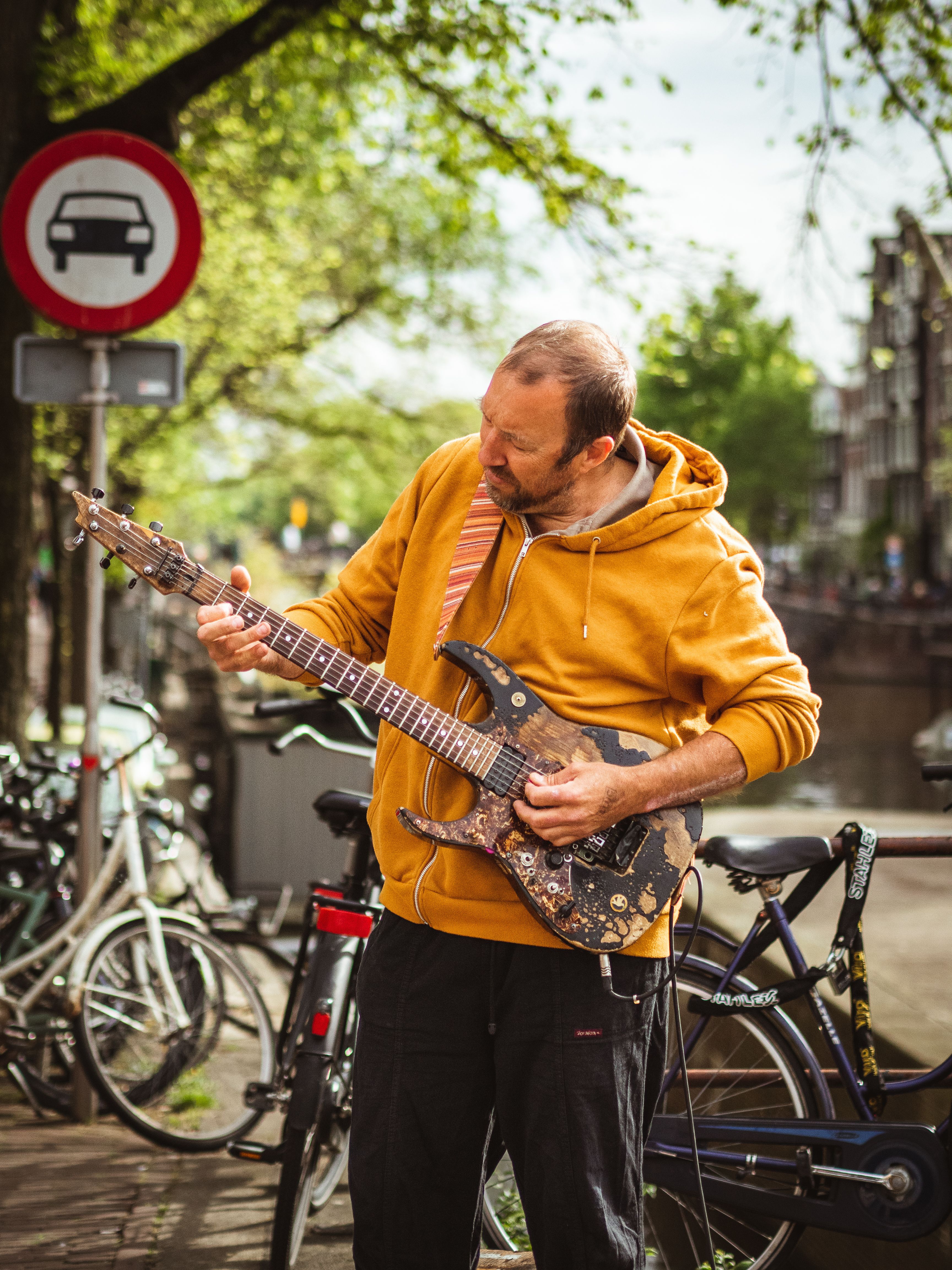 Musician with electric guitar performs outdoors in Amsterdam street scene.
