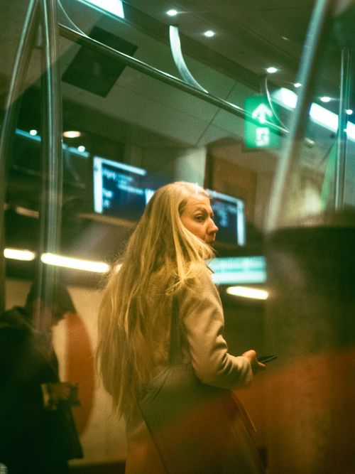 Free A woman with long blonde hair waits at a metro station in Amsterdam with a reflective ambiance. Stock Photo