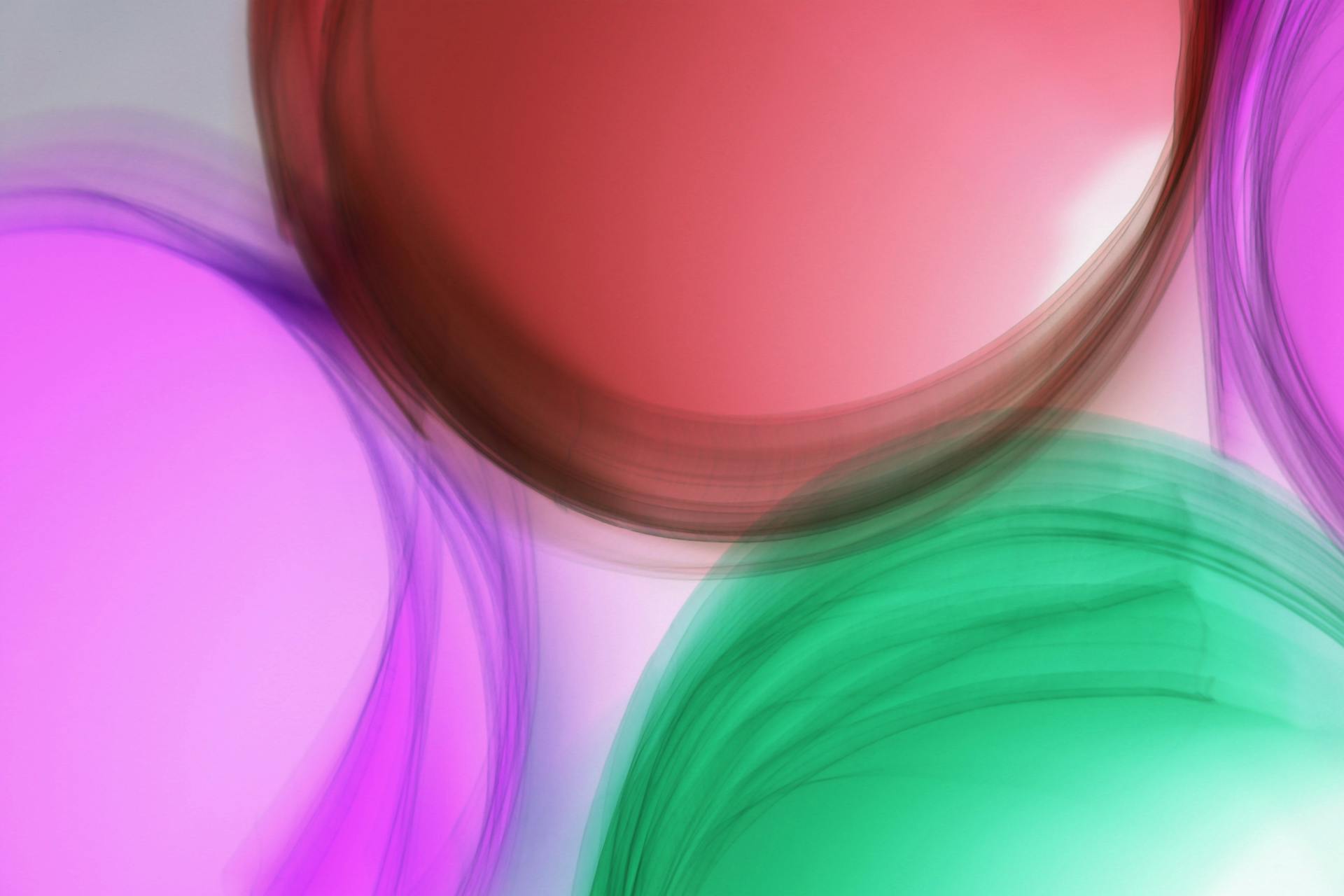 A vibrant abstract image depicting blurred circles in pink, red, and green hues.