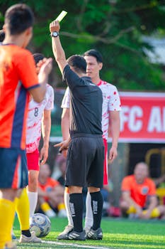 Referee shows a yellow card to a player during a soccer match in Hanoi, Vietnam.