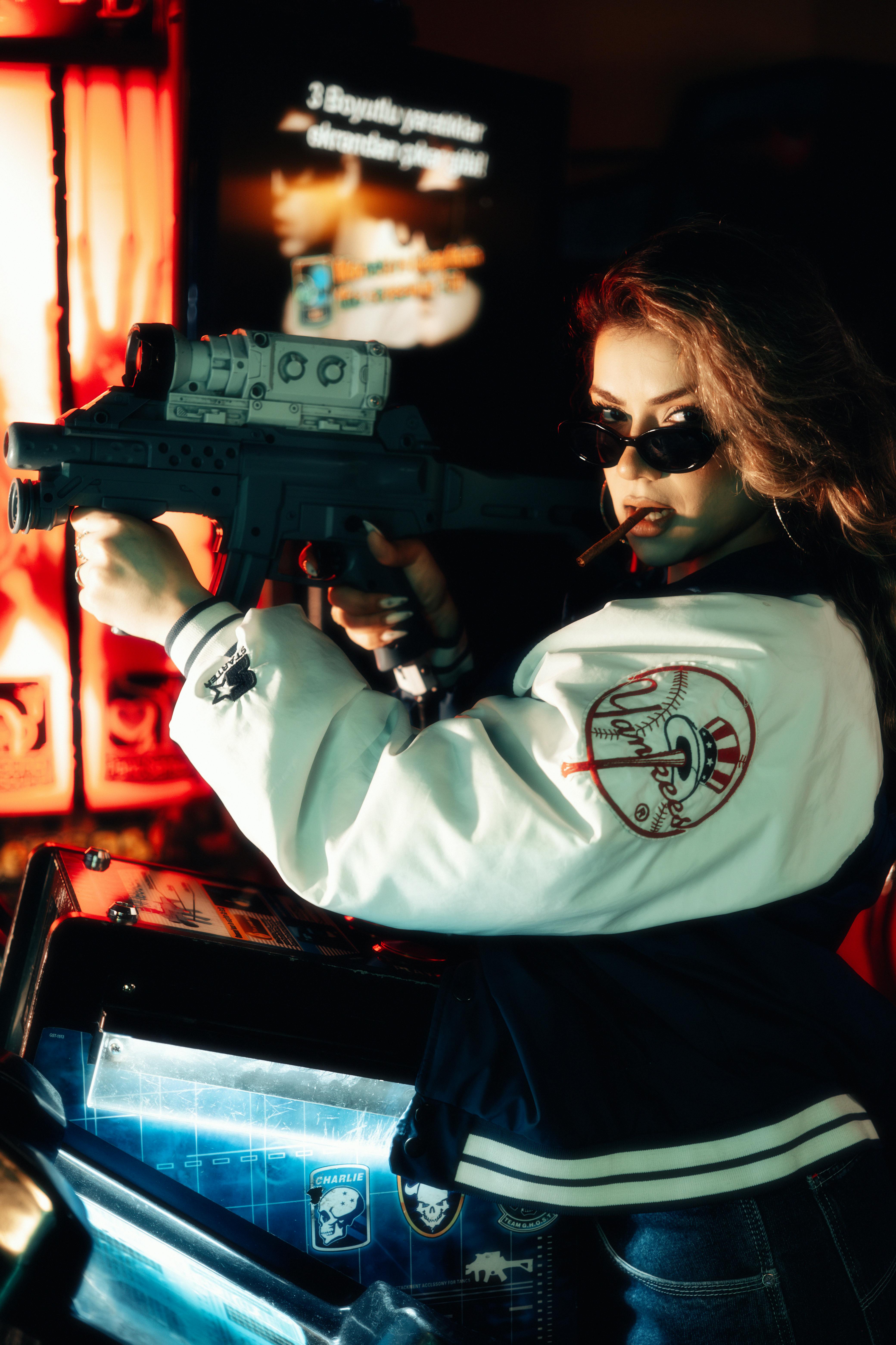 Woman with toy gun in a neon-lit arcade setting.