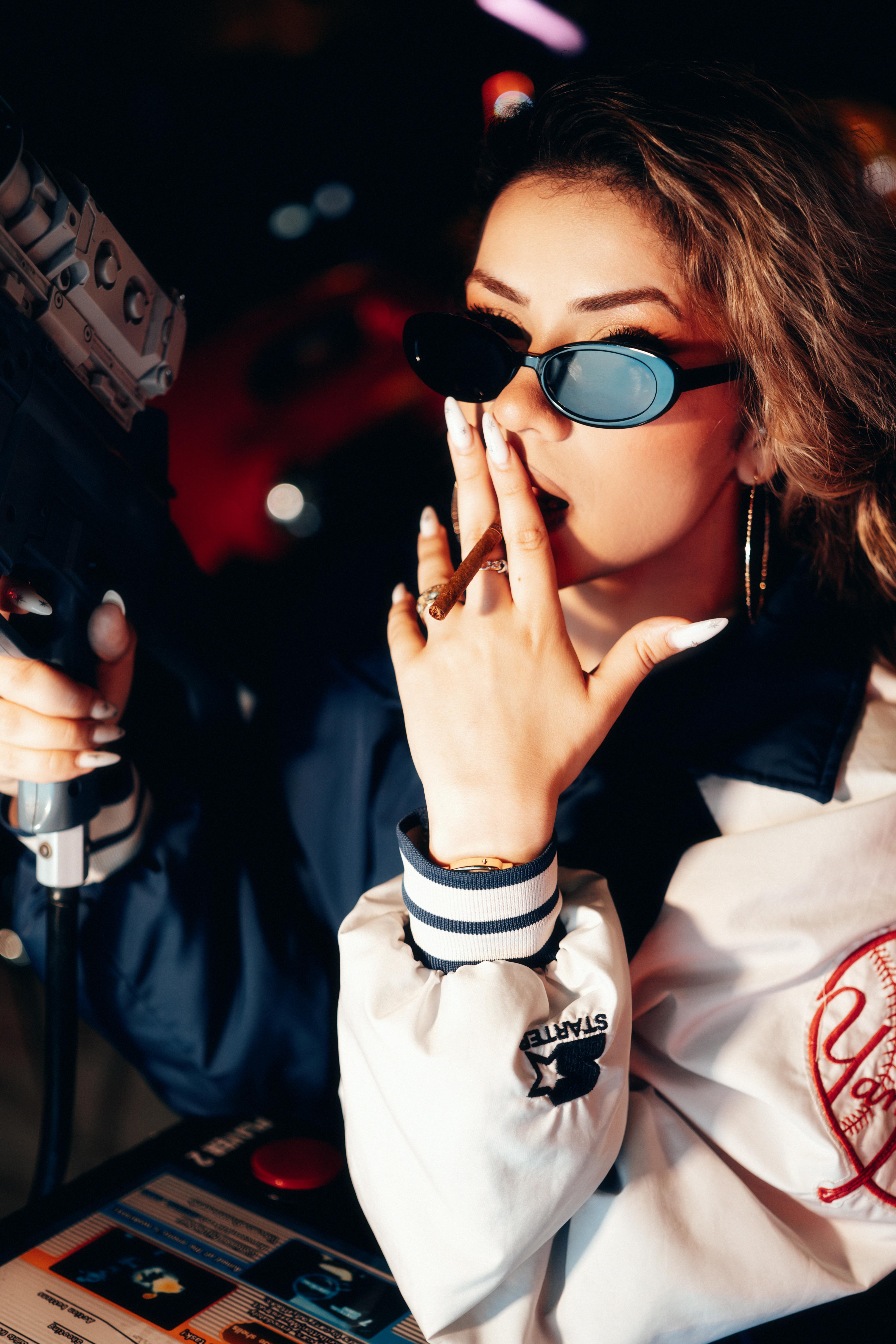 Miễn phí Người phụ nữ sành điệu đeo kính râm đang chơi trò bắn súng đồ chơi ở khu trò chơi điện tử, toát lên vẻ sành điệu. Ảnh lưu trữ