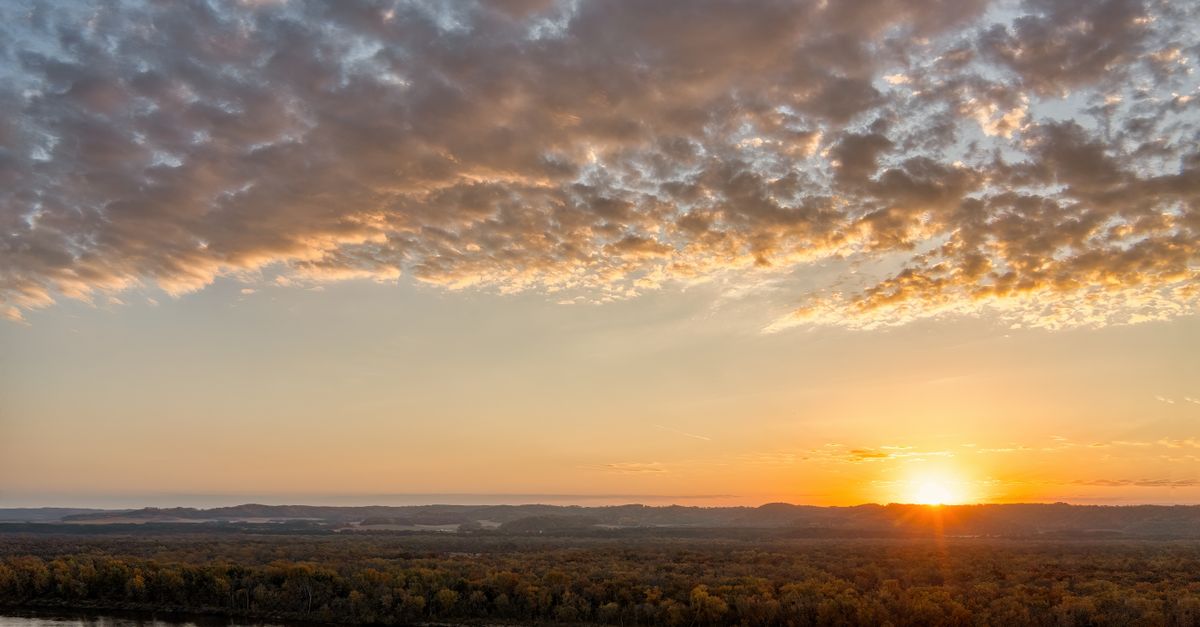 A beautiful autumn sunrise over the Mississippi River with vibrant skies.