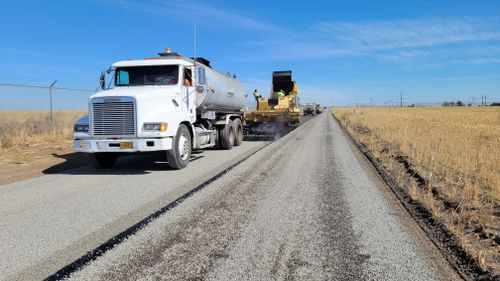 Free Paving of a rural road in Hermiston, Oregon with construction vehicles and workers visible. Stock Photo