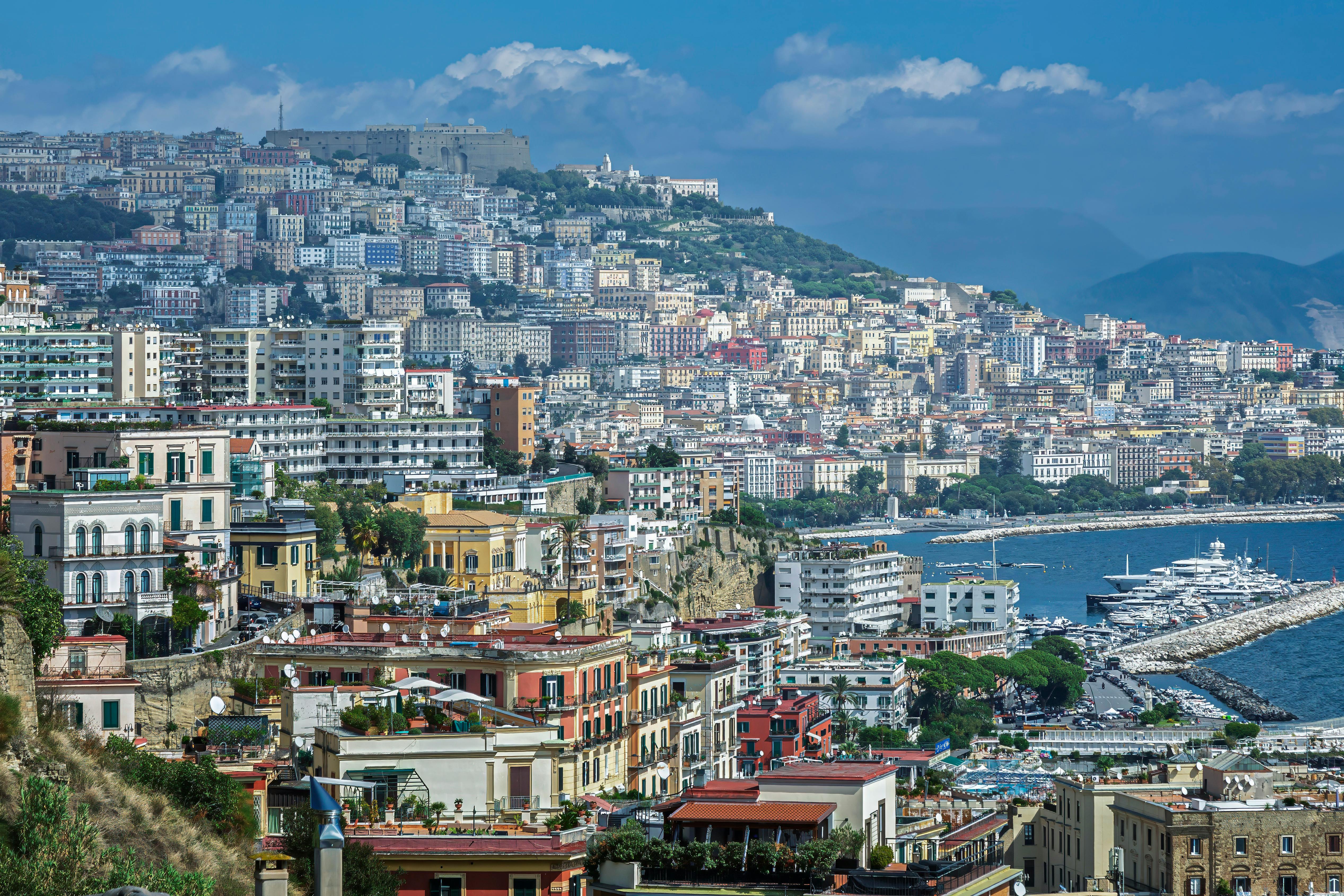 A breathtaking view of the colorful buildings and coastline of Naples, Italy, showcasing the vibrant city life and stunning sea.