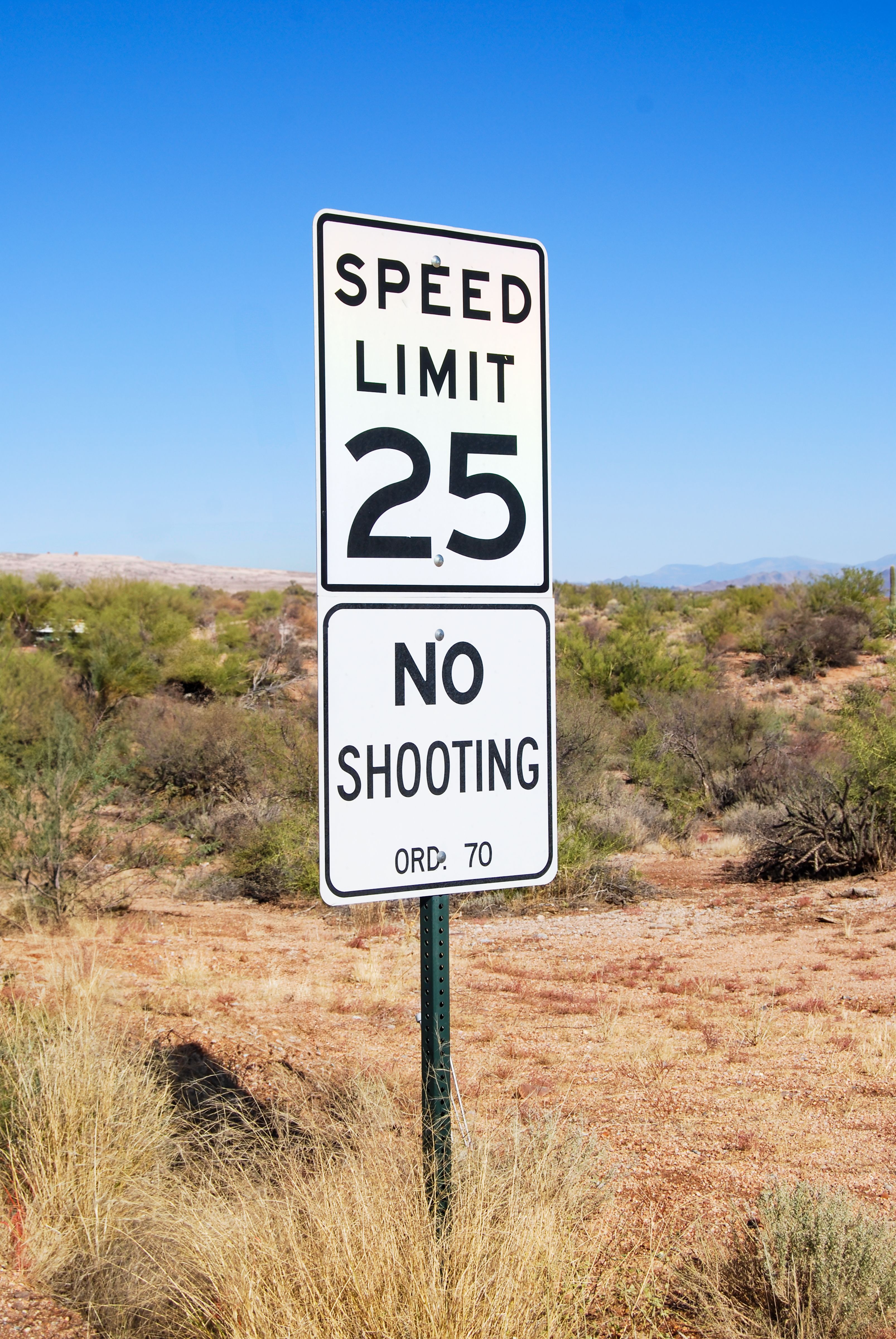 A speed limit and no shooting sign in the Arizona desert landscape.
