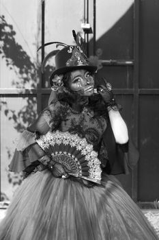 Black and white portrait of a woman in Day of the Dead attire, featuring intricate face paint and traditional dress.