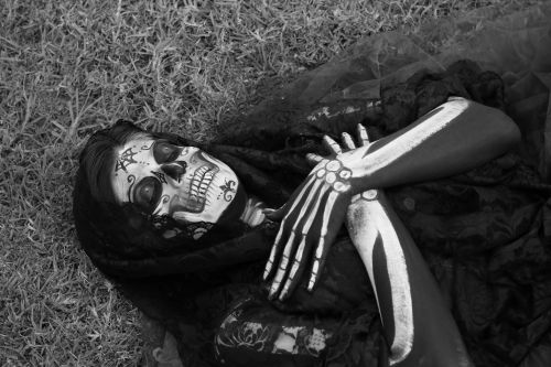 Free Person with skull face paint and skeleton body art lying on grass. Stock Photo