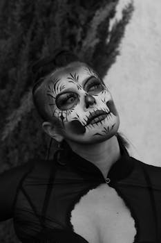 Black and white portrait of a woman wearing intricate Day of the Dead makeup.