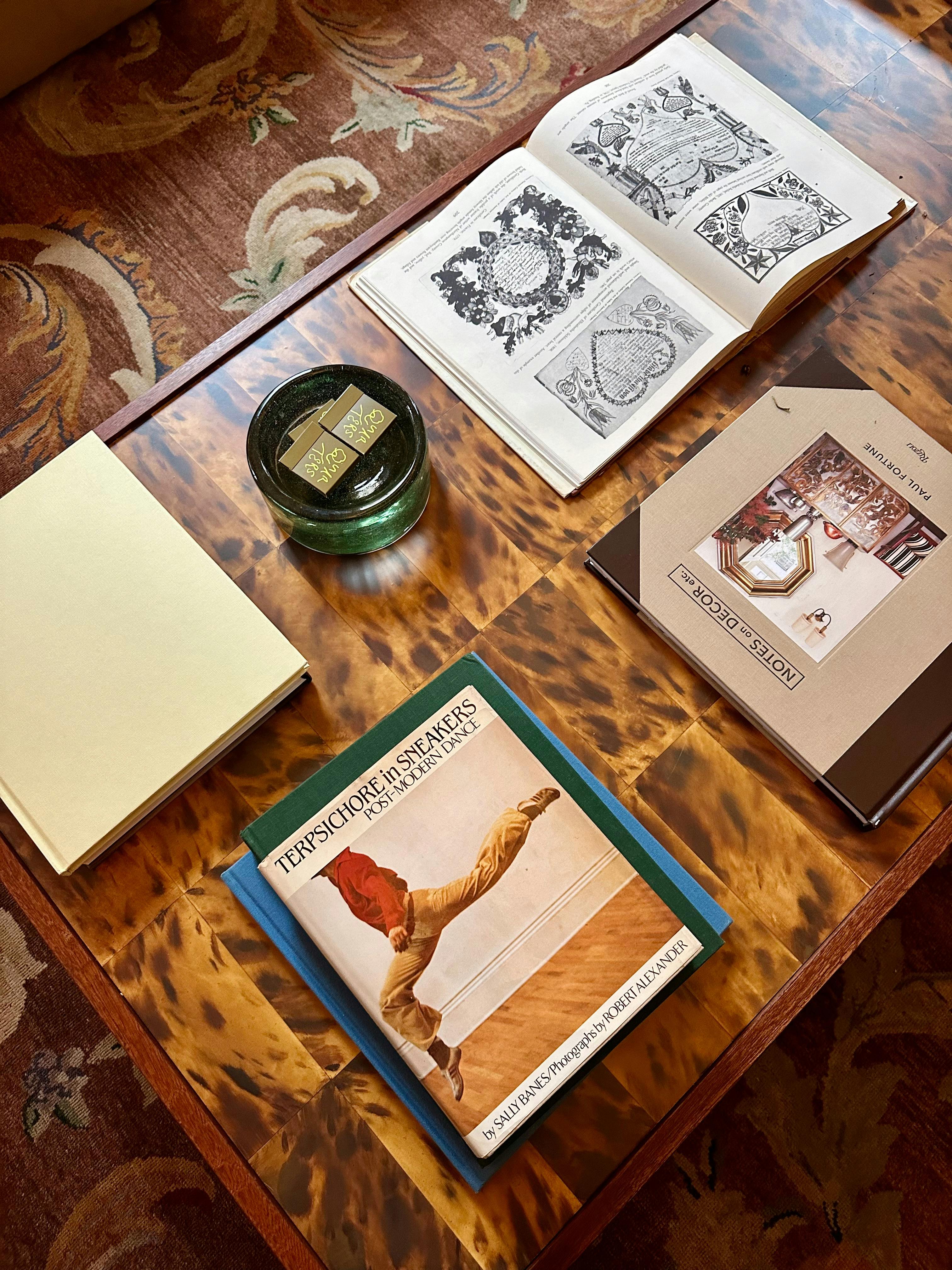 Stacked art and fashion books on a styled coffee table in warm interior light