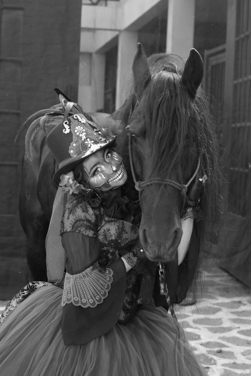 Free Woman in colorful costume embraces horse. Artistic, festive atmosphere in black and white. Stock Photo