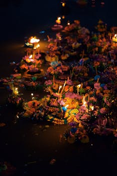 Floating krathongs with candles on water during Loy Krathong festival in Bangkok.