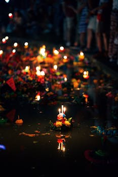 Candles on colorful floats in a waterway during Loy Krathong festival in Bangkok, Thailand.
