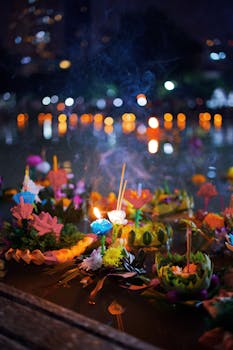 Colorful krathongs float on water during Bangkok's Loi Krathong festival, lit by candlelight at night.