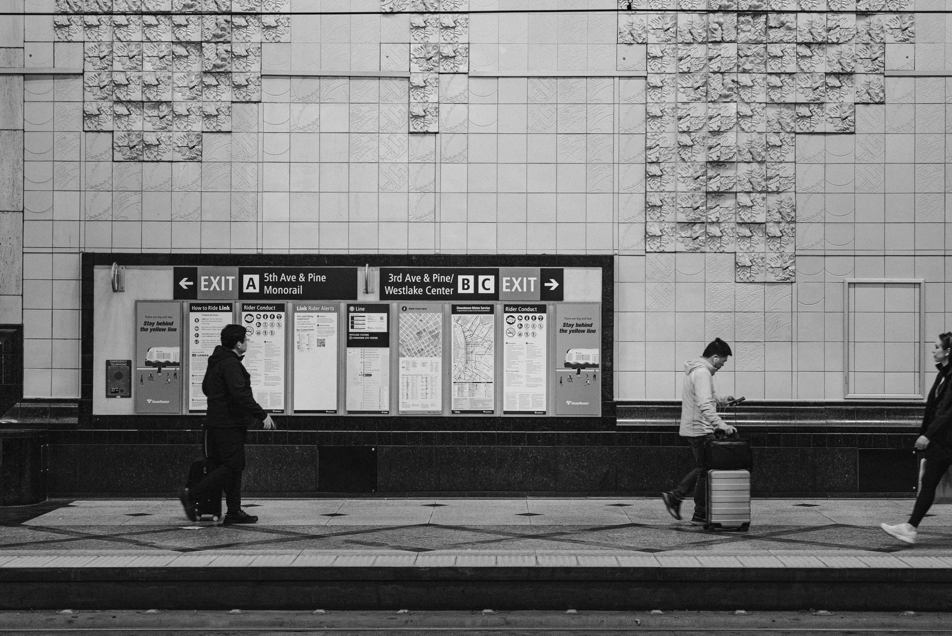 Black and white scene of people at a Seattle train station, capturing urban transit life.