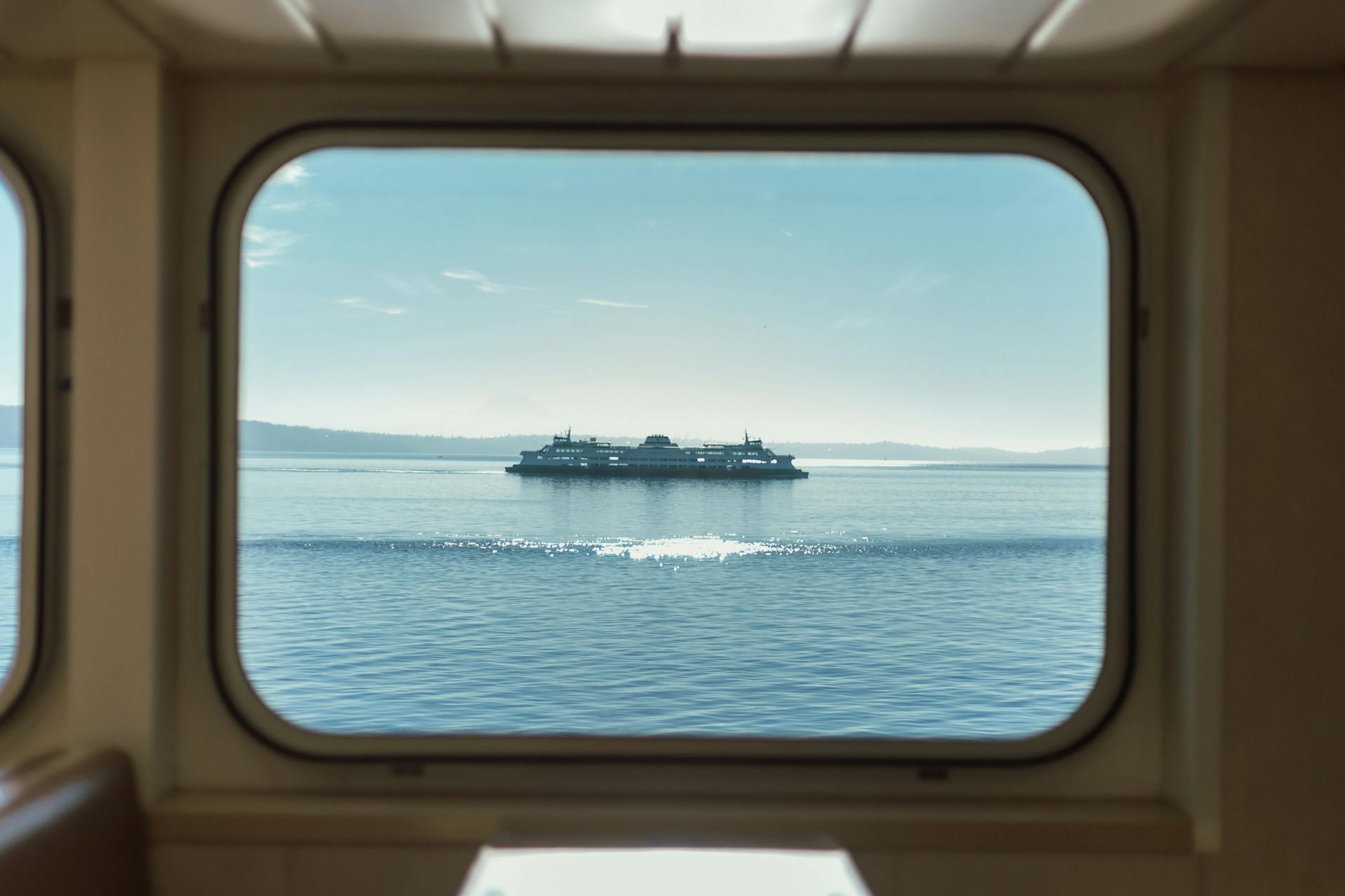 Serene view of a ferry passing by as seen from a cabin window, capturing Seattle's coastline.