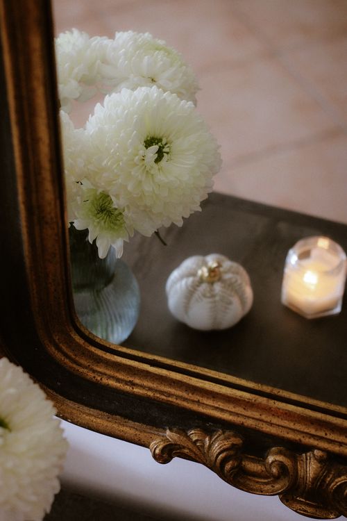 Free Charming white flowers reflected in a vintage mirror with a candle and pumpkin decor. Stock Photo