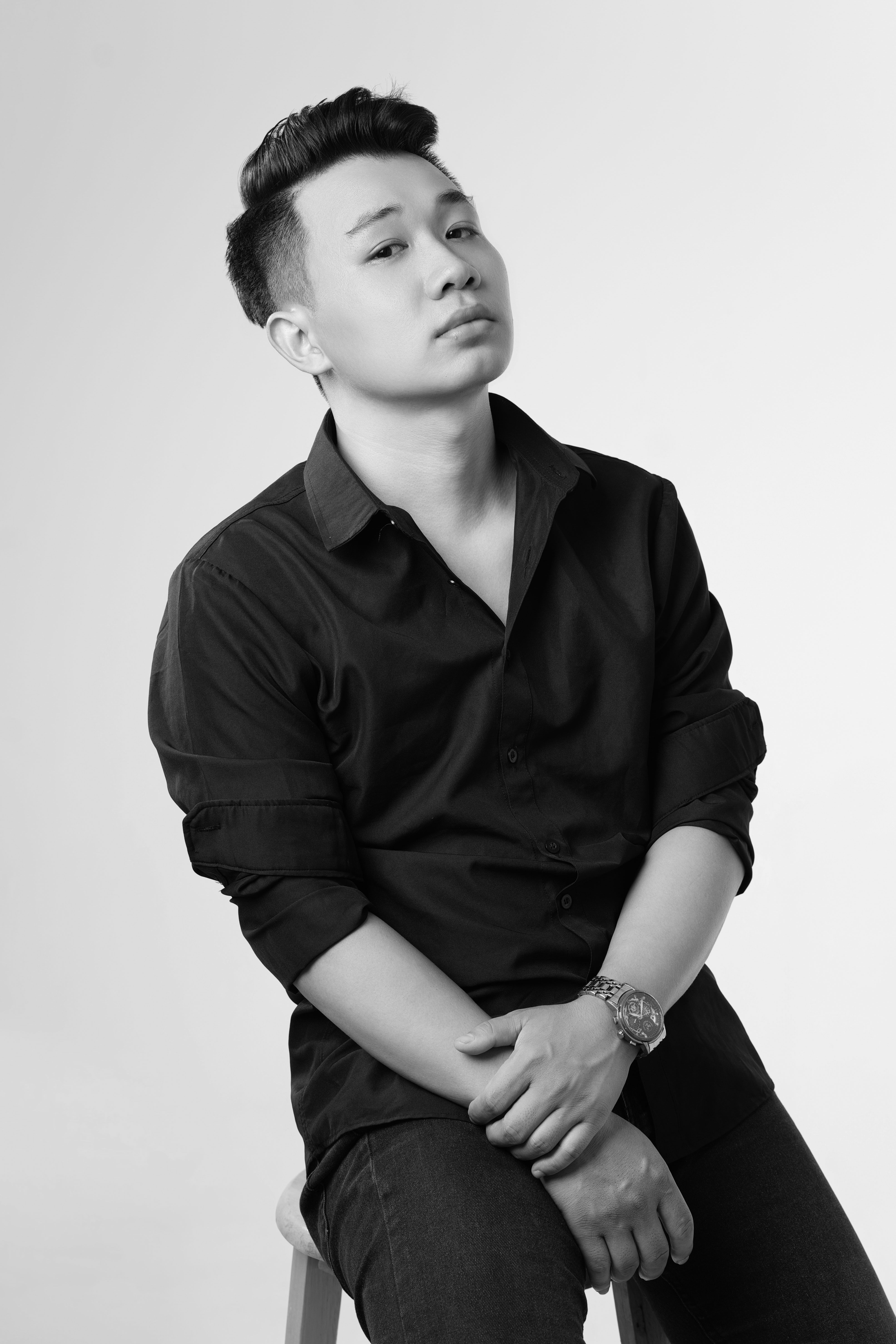 Monochrome portrait of a young man in a casual pose with a thoughtful expression.