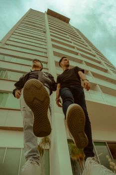 Low-angle view of two young men with a modern skyscraper background.