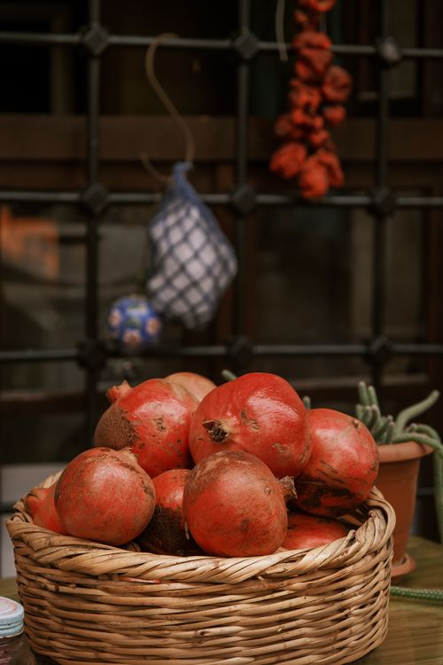 Free Rustic display of ripe pomegranates in a wicker basket with a cozy background. Stock Photo