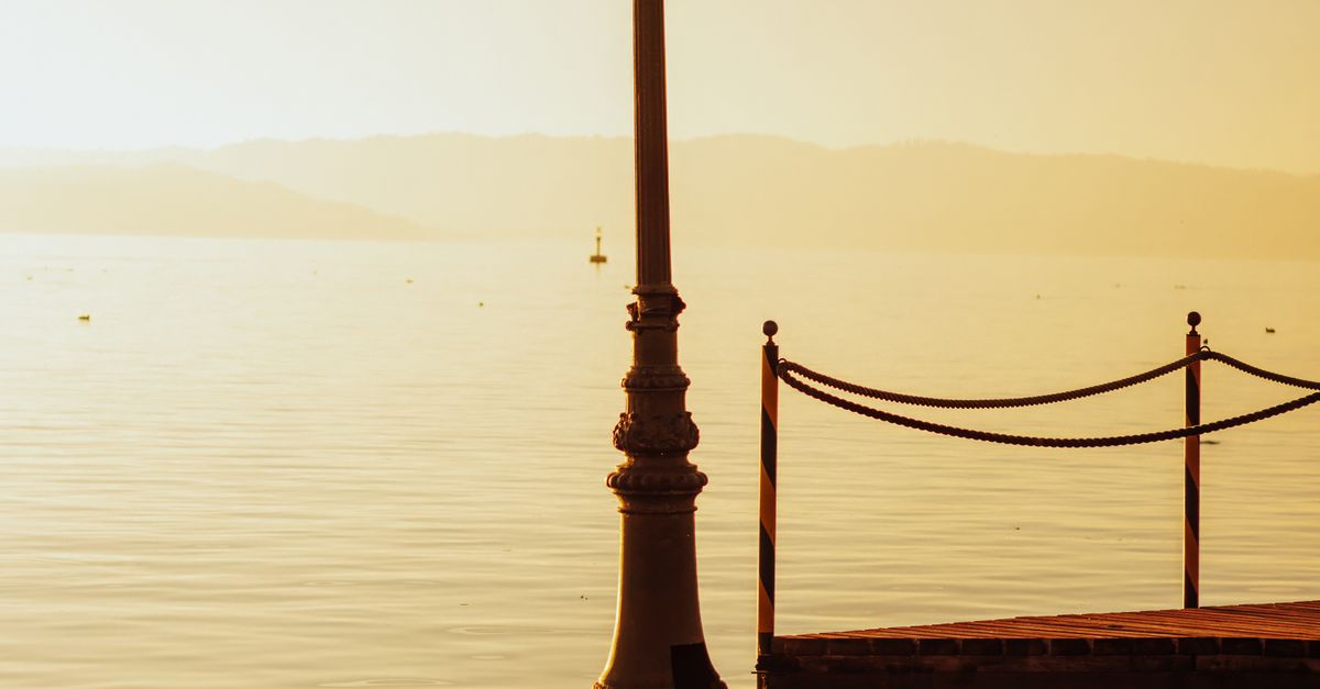Light Posts Sunset Serene Waterfront at Sunset with Lamp Post · Free Stock Photo