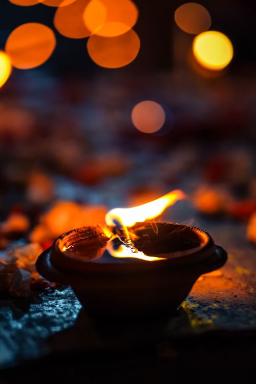 Free A traditional clay diya lamp flickering with flame, symbolizing Diwali spirit. Stock Photo