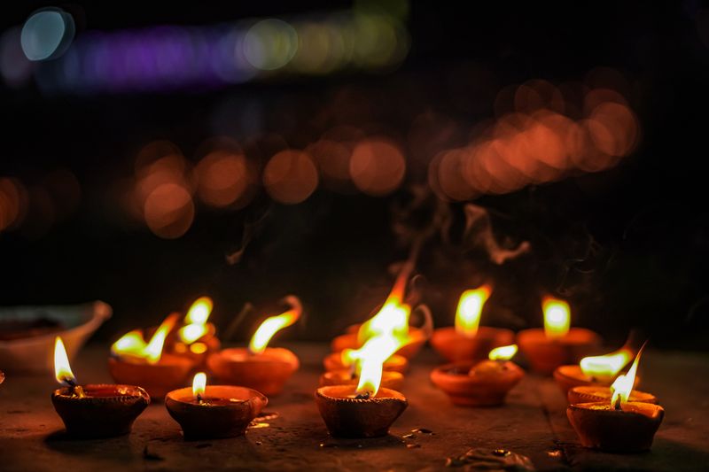 Rows of glowing oil lamps create a festive and tranquil ambiance during a nighttime celebration.