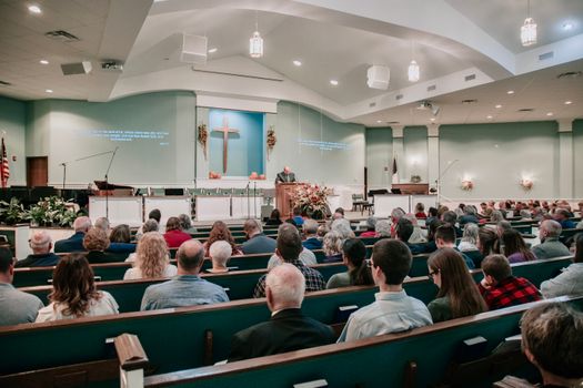 A large congregation listens to a speaker in a modern church setting.