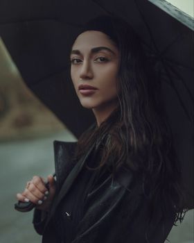 A serene portrait of a woman under an umbrella, capturing the essence of rain.