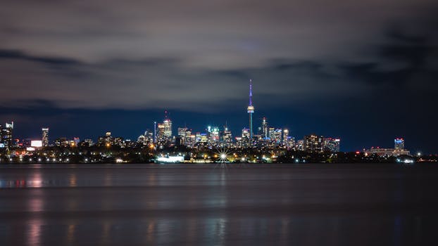 Stunning view of Toronto's skyline with the illuminated CN Tower across the lake at night.