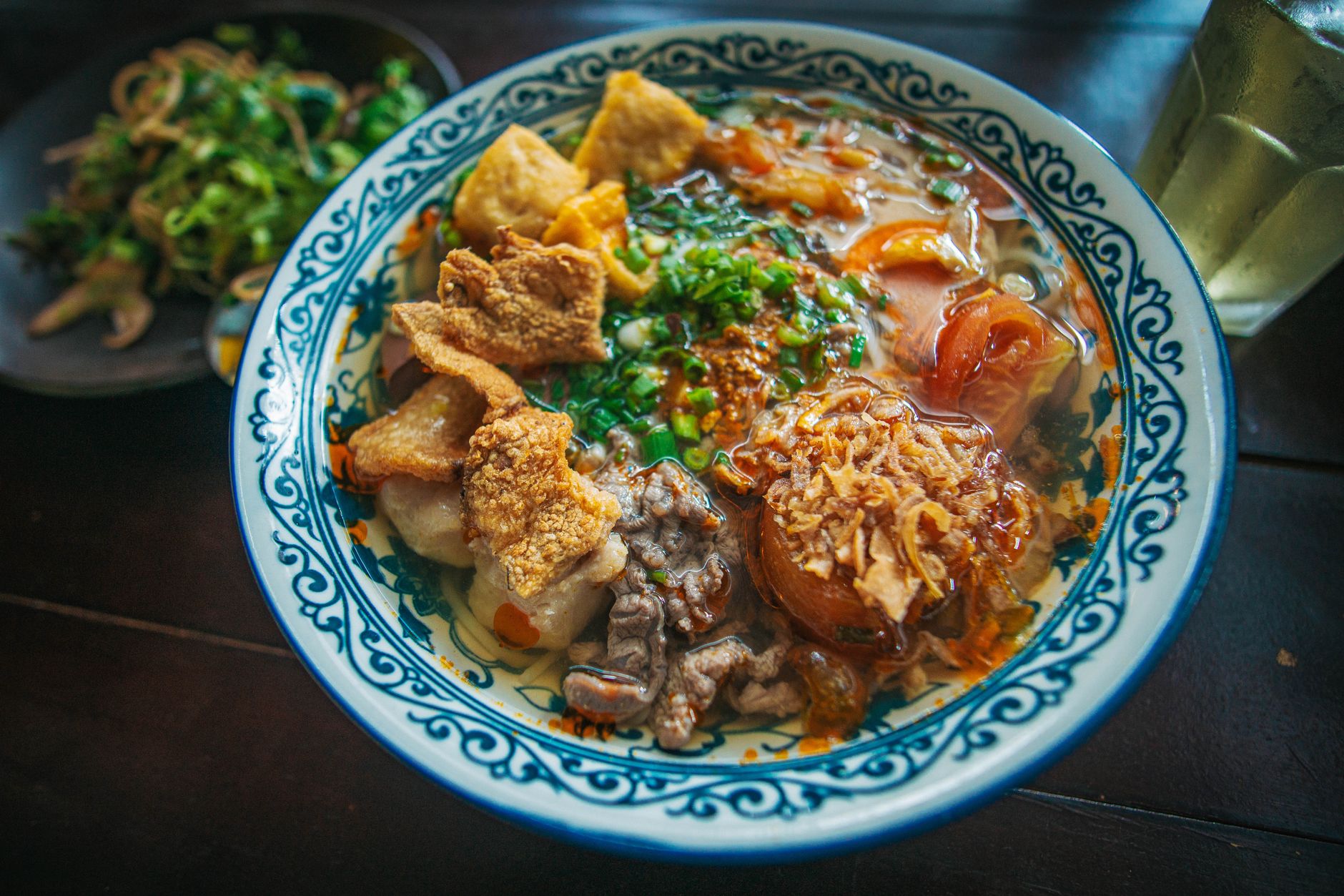 A vibrant bowl of Vietnamese pho garnished with herbs and crispy toppings.